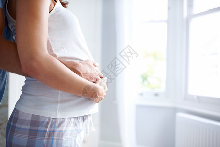 富有成果的开端——复制空间 一个年轻女性怀孕后肚子被她和她男朋友抱住的侧面景象背景