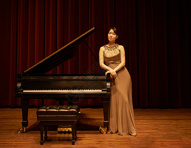 钢琴开业素材开业之夜 一个年轻女子站在钢琴旁 在音乐会的尽头背景