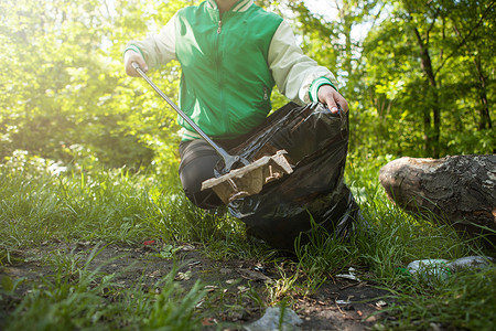志愿者在森林里捡垃圾森林女士环境回收生态采摘捡垃圾塑料收集公园背景图片