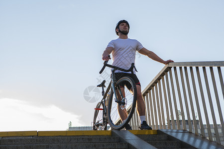骑士城里的男骑自行车者碎石齿轮运动街道天空车辆运输安全自行车头盔背景