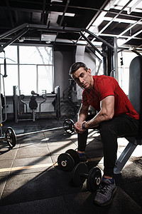 体操馆的男性运动健壮运动员男人健身房训练哑铃健美肌肉背景图片
