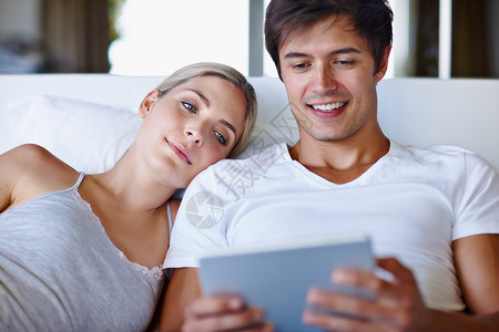 一个快乐的情侣躺在床上 一起用数字平板电脑 你和他在一起吗?背景图片