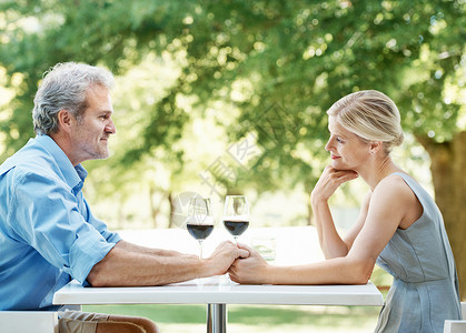 快乐的成熟情侣坐在桌前 拿着两杯葡萄酒 在户外举手 (笑声) (掌声)背景图片