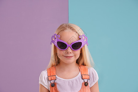古怪而多彩……这就是她的个性 一个可爱的小女孩在彩色背景下戴着滑稽的太阳镜背景图片