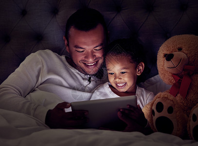 晚上 平板电脑和男人和女孩躺在床上看电影 连续剧或娱乐节目 爱 微笑和快乐的父女在家里的卧室里放松 玩网络游戏或阅读数字电子书背景图片