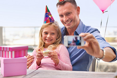 生日快这么快就长大了 一个快乐的男人在她生日的时候给自己和他年轻女儿拍照的一张照片被拍到了背景