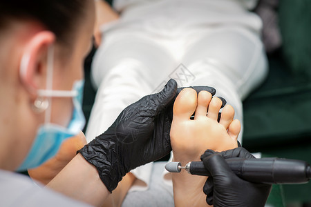 美容院的一位修脚师 在女性脚掌上 进行切除脚印手术脚趾沙龙组织皮肤科呵护手套皮肤钻头服务身体美丽高清图片素材