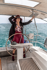 极富魅力的中年女子在夏日主持游艇 豪华夏季冒险 户外活动微笑运输蓝色血管船长旅行队长巡航奢华女士背景图片