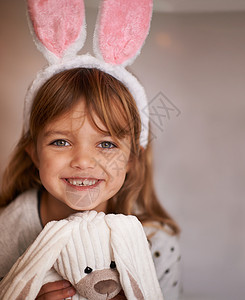 抱着包兔子可爱的伴侣 一个可爱的小女孩的画像 她戴着兔子耳朵 抱着她的玩具兔子背景