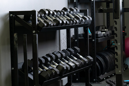 Dumbbell家的墙壁健身房模糊了装有坚固设备 从黑色运动衣中取出用于健健美健壮 重体力建筑背景图片