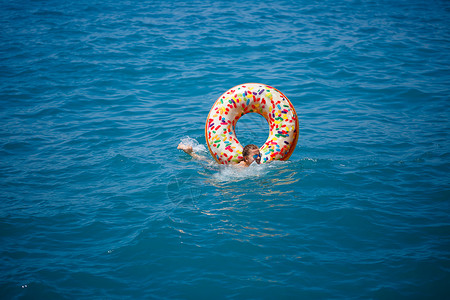 漂浮在透明绿松石海中的充气大甜甜圈上的年轻女子 一位苗条的女士在土耳其 埃及 地中海度假时放松身心戒指泳装酒店天线日光浴海滩电脑背景图片