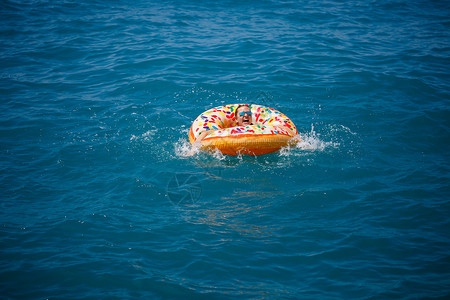 漂浮在透明绿松石海中的充气大甜甜圈上的年轻女子 一位苗条的女士在土耳其 埃及 地中海度假时放松身心游泳海滩乐趣水池柔焦酒店比基尼背景图片