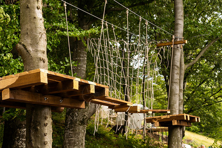 绳索摆动在绳索公园安全设备中徒步登上绳子攀爬中心绳索平衡活动环境风险危险树梢闲暇森林冒险背景
