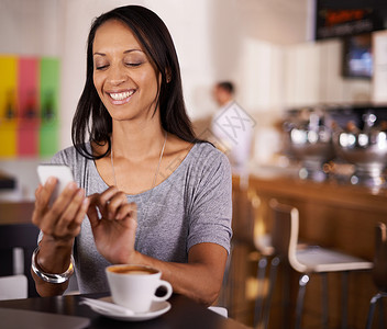 喜欢她的新手机 一个有魅力的女人坐在咖啡店里时发短信呢背景图片