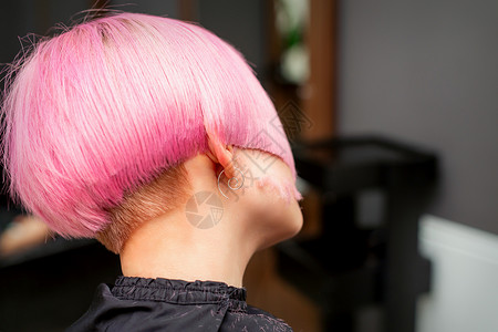 剪短发的女孩在美发沙龙中为年轻模特的后视造型和剪染的粉红色头发 粉色短发化妆品治疗染色女性理发店女孩客户护理美丽工作室背景