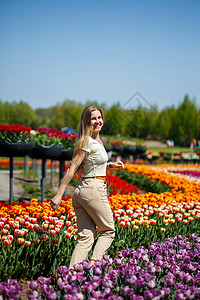 穿白色裙子的女孩跑在郁金香中间 田里有黄色和红色的郁金香生长花园植物公园享受种植植物群喜悦农业场地背景图片