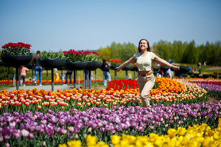 穿白色裙子的女孩跑在郁金香中间 田里有黄色和红色的郁金香孩子植物群公园生长植物花园乐趣幸福晴天企业背景图片