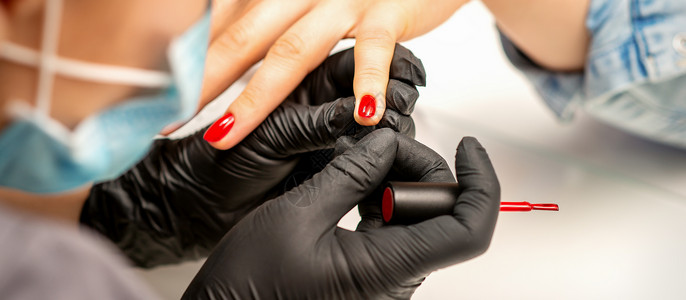 在美容院的一只雌性指甲上涂着红色清漆 穿着橡皮黑手套的美甲师傅贴近了她的身影服务工作抛光温泉横幅美甲师刷子奢华治疗身体背景图片