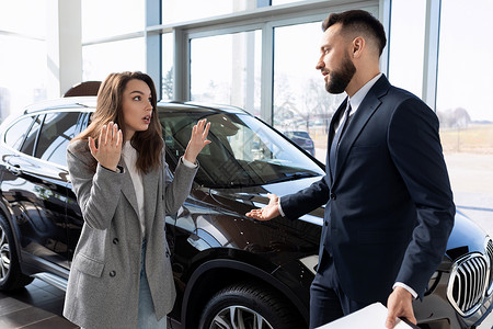 一名妇女在与汽车经销商代表争论的经销商中维护自己的权利背景图片