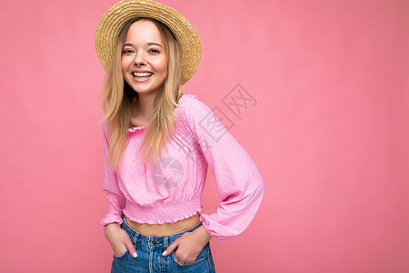 女式帽年轻漂亮的女人穿着时尚的粉色夏季衬衫和时髦的草帽 积极的女性表现出面部情绪 有趣的模型隔离在粉红色背景与自由空间金发女郎情绪化帽背景