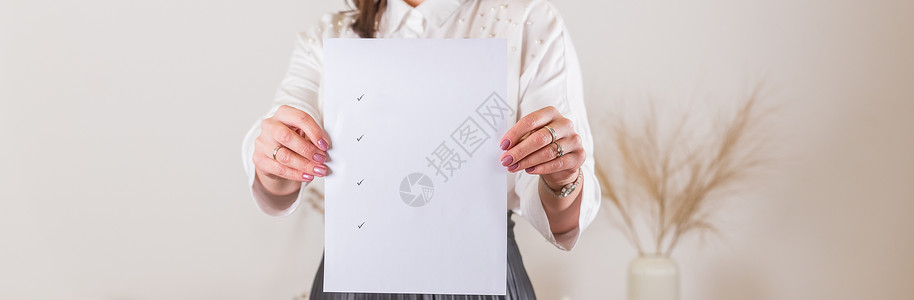 帮助海报女人拿着一张带有复选标记的空白纸 在女性手中的白纸海报 平面设计师作品集的空白模板 在商业 博客 教育方面制定计划背景