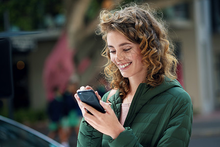 快乐的女人 在城市旅行期间使用社交媒体 互联网和 5g 网络连接在手机上微笑和打字 年轻女性在城市街道上使用手机应用程序调情背景图片