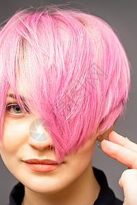 粉色发廊元用手梳发的发型师正在检查 并修补短粉红色的发型 在一个发廊里 年轻白种女人手臂工作梳子成人造型师粉色女士沙龙治疗美容师背景