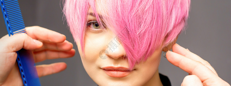 粉色发廊元用手梳发的发型师正在检查 并修补短粉红色的发型 在一个发廊里 年轻白种女人梳子沙龙粉色女孩理发造型顾客治疗美容师女性背景
