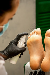 一个女人在美容院里用润滑剂喷洒女性的脚 来修脚和修脚病学卫生手套皮肤客户病人指甲医生程序打扫化妆品高清图片素材