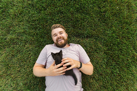 男人有小猫在草地上躺着玩耍友谊爱爱动物和宠物拥有者概念男性婴儿享受哺乳动物村庄猫咪说谎自由胡须成就背景图片