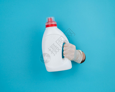 橡皮手套一个女人拿着一瓶白色的洗涤剂 女人的手从蓝纸背景中伸出来蓝色房子家庭女性卫生工具瓶子产品家政家务背景
