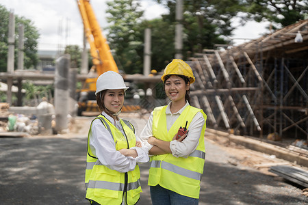 站在建筑工地的两名亚洲女建筑承包商的肖像背景图片
