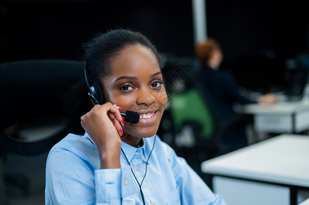 非洲年轻女性在耳机上与客户交谈 呼叫中心的女雇员 请问人士商务电脑帮手工作顾客情感职业女孩公司背景图片