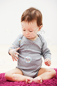 灰色漂浮泡泡泡泡的乐趣 一个可爱的小男孩试图触摸漂浮在他身边的气泡背景