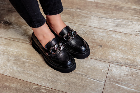 老式宝马系列穿黑色牛仔裤和黑带鞋的女子腿 黑皮鞋紧贴靴子女性鞋类工作室女孩季节女士店铺衣服购物中心背景