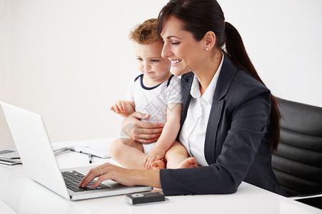 微笑的工作母亲在用笔记本电脑工作时怀着一个婴儿 而她却笑着要生孩子背景图片