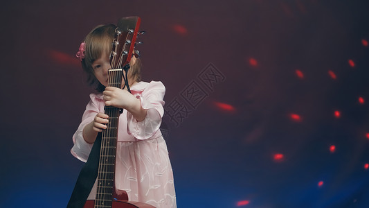穿粉红旧礼服的小女孩 像双低音一样弹声吉他轻音乐衣服孩子们中提琴家庭大提琴才俊戏服宝宝爱好背景图片