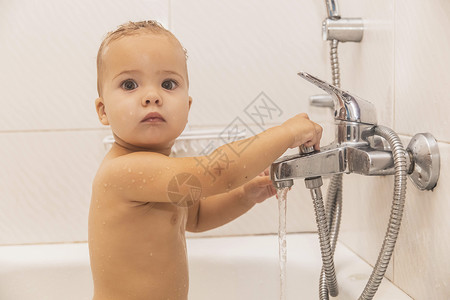 浴室里的婴儿浴池 紧握着自来水龙头高清图片