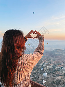 坐热气球的女孩在土耳其卡帕多西亚观看热气球的日出快乐妇女旅行航班旅游悬崖自由胡同娱乐岩石飞机游客背景