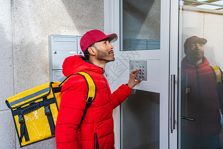 电梯是不能敲非裔美国人食品运送工人在门口敲着公寓街区的门铃 他们把门铃敲响背景