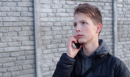 一个15岁男孩的肖像 手拿着智能手机背景图片