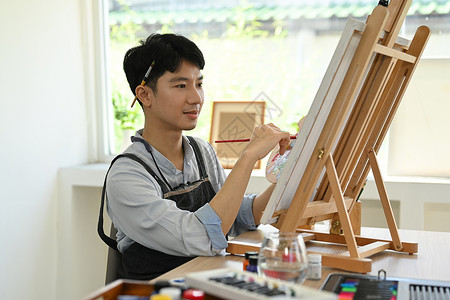 亚洲艺术中心坐在画布和水彩画画像前的康纳以亚洲人为中心的男性艺术家 闲暇活动概念背景