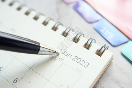 办公服务台2023年日历新年蓝色桌子紧迫感背景粉红色电脑铅笔笔记本背景图片