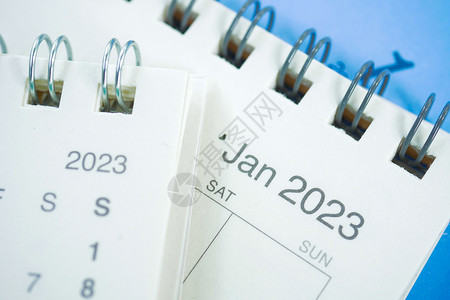 办公服务台2023年日历笔记本紧迫感桌子电脑粉红色铅笔新年蓝色背景背景图片