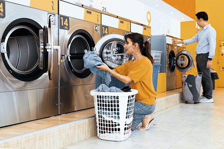 旧投币式洗衣机亚洲人使用合格的洗衣机 在公共房间里店铺洗涤男性女士服务家庭篮子衣服烘干机成人背景
