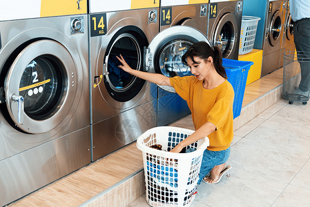 旧投币式洗衣机亚洲人使用合格的洗衣机 在公共房间里烘干机衣服墙纸洗涤自助成人店铺家庭男人篮子背景