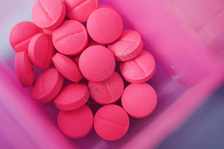 在桌上的药盒里 包着粉色止粉色医用药丸剂量药物盒子塑料药品胶囊日程背景图片