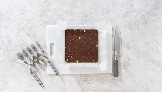 巧克力奶油软糖平铺坚果刀具傻事烹饪食物砧板高架甜点白色背景图片