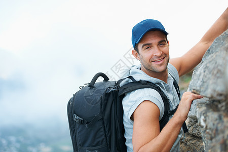 茵他侬山年轻登山者在摄影机上微笑 他正在攀升悬崖的顶部 (笑声)背景