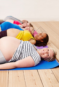 进行呼吸锻炼 一群孕妇躺在运动垫子上躺着——肖像画;以及一些怀孕妇女背景